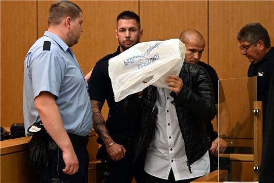 Der Angeklagte verdeckt vor Beginn des Prozesses im Gerichtssaal in Aachen sein Gesicht.