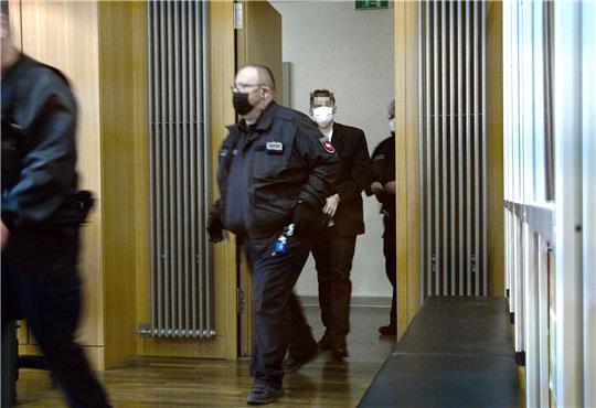 Der Angeklagte wird in Handschellen vorgeführt und von Justizbeamten begleitet. Foto: Neddermeier