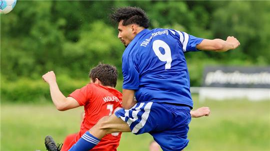 Zwei Fußballspieler im Zweikampf, einer in rotem Trikot mit der Aufschrift 'WOLFER' und einer in blauem Trikot mit der Nummer 9 und der Aufschrift 'TSG Harzburg'