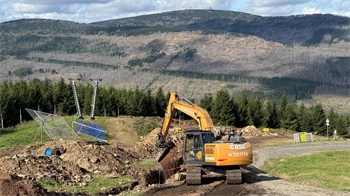 Das Foto zeigt einen Bagger bei der Arbeit und im Hintergrund den höchsten Berg des Harzes, den Brocken.