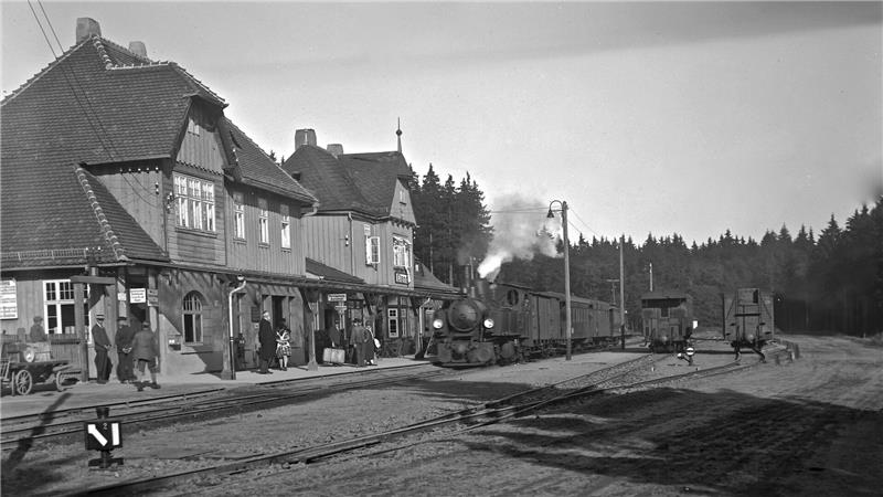 Das alte Schwarz-Weiß-Foto zeigt einen alten Bahnhof und eine alte Dampflok.