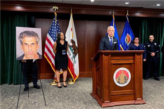 Der  Bezirksstaatsanwalt von Los Angeles, George Gascon, steht während einer Pressekonferenz neben dem Foto von Fernsehproduzent Eric Weinberg.