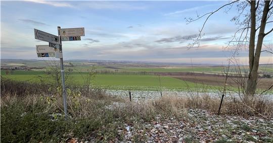 Ein Schild im Vordergrund, im Hintergrund landwirtschaftlich genutzte Flächen.
