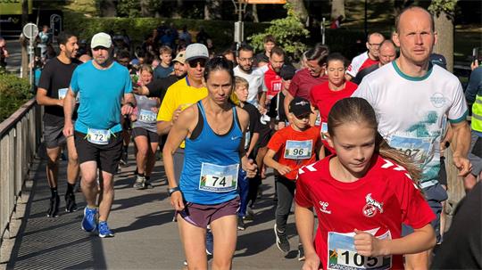 Eine große Gruppe Menschen in Sportkleidung läuft über eine Straße.