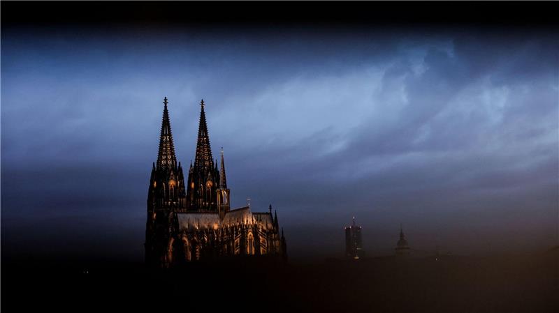 Bilder des Tages Der Dom in Köln ist am Morgen durch ein Geländer gesehen beleuchtet.
