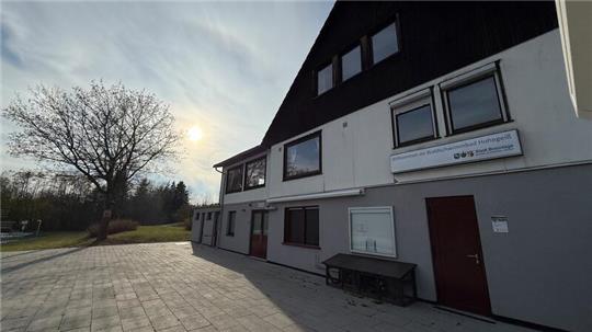 Das Foto zeigt ein Haus und die Abendsonne im Hintergrund.