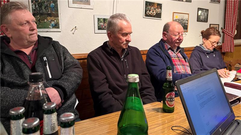 Das Foto zeigt eine Frau und drei Männer, die auf einer Bank vor einem Tisch sitzen.