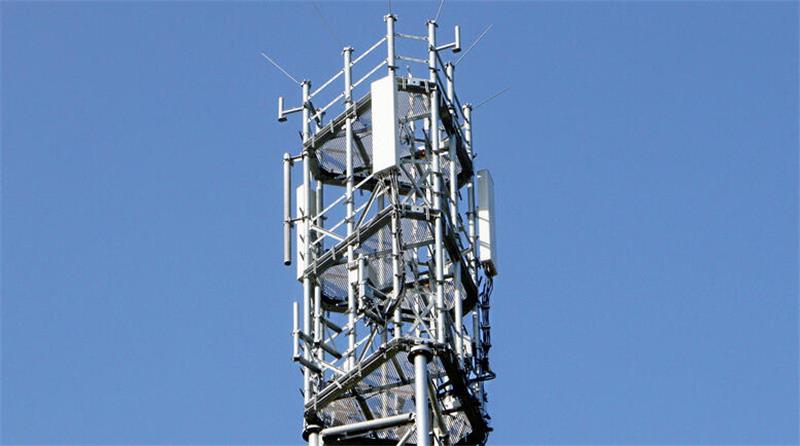 Spitze eines Mbilfunkmastes mit Sendeanlagen vor blauem Himmel