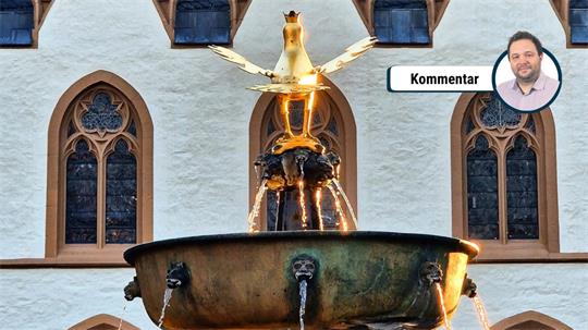 Brunnen mit einem goldfarbenen Pferd als Brunnenfigur vor einer weißen Fassade mit gotischen Fenstern