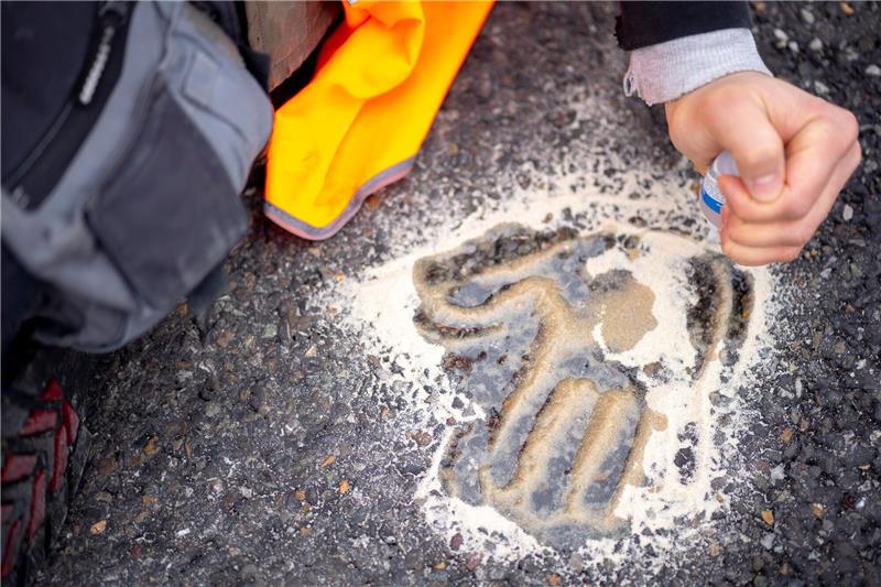Klimaschützer-Gruppe will auf Klebeaktionen verzichten Der Handabdruck eines Aktivisten klebt auf der Straße.