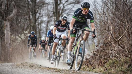 Gruppe von Radrennfahrern auf einem unbefestigten Waldweg mit Staubentwicklung