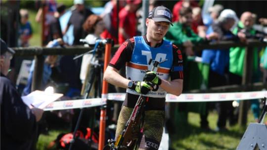 Der Harzer Biathlet Hans Köllner stellt sein Kleinkalibergewehr für die nächste Laufrunde in den Holzständer. Anders als im Winter auf Skiern wird die Waffe in Laufschuhen nicht mit auf die Strecke genommen.