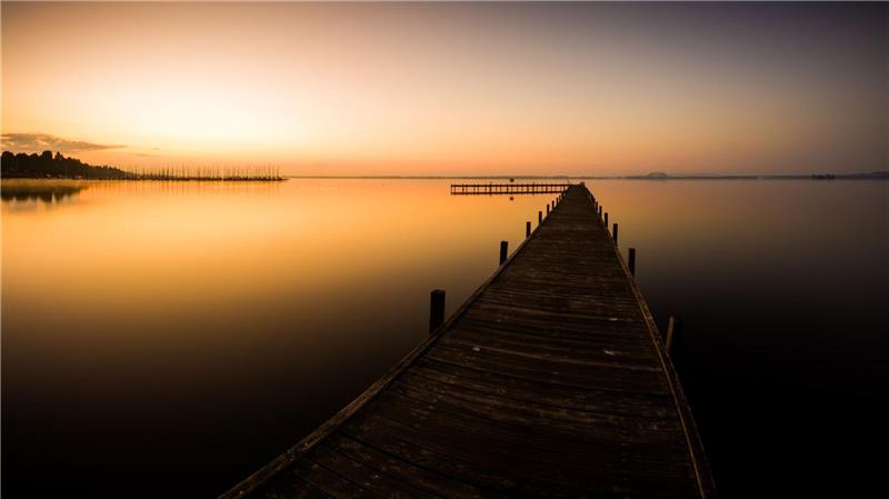 Bilder des Tages Der Himmel über einem Steg am Steinhuder Meer in der Region Hannover ist bei Sonnenaufgang orange.