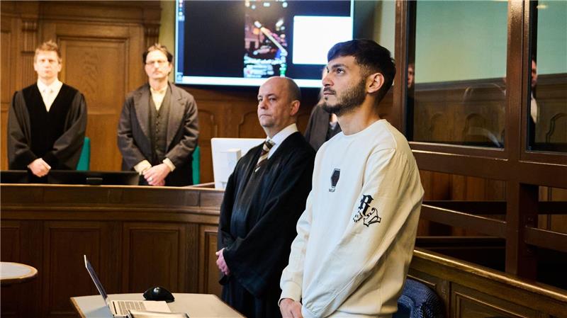 Der Influencer (r), der eine Silvesterrakete in eine Wohnung geschossen hat, steht mit gefalteten Händen im Gerichtssaal neben seinem Rechtsanwalt.