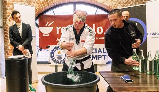 Der Kampfsportler Muhamed Kahrimanovic beim Versuch, mit verbundenen Augen und einem rohen Ei in der Hand Glasflaschen zu zerschlagen.