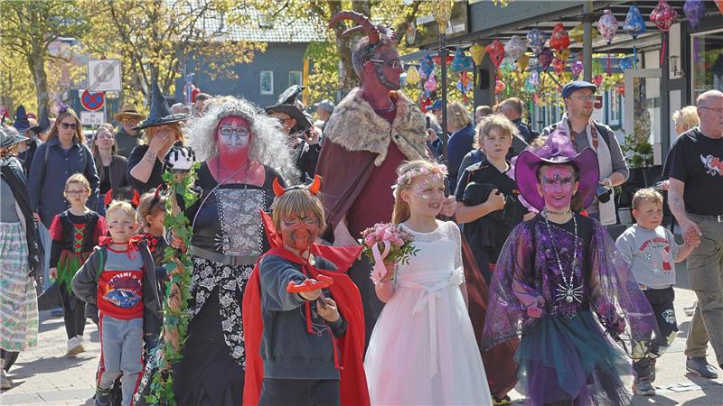 Gruppe von Kindern und Erwachsenen in fantasievollen Kostümen bei einem Umzug auf einer belebten Straße