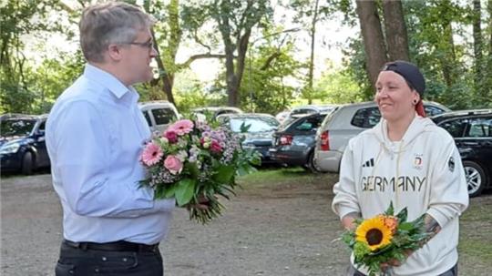 Der Landesgeschäftsführer des Niedersächsischen Sportschützenverbandes, Karsten Nesbor, überreicht Jolyn Beer Blumen.