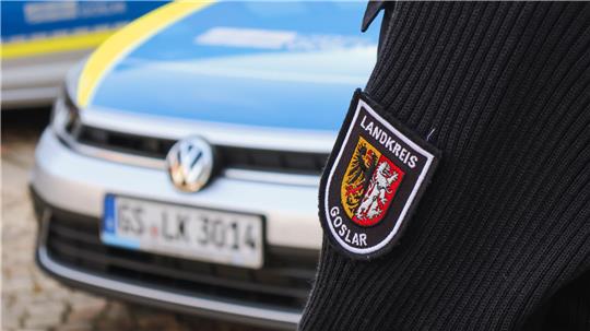 Ein Mitarbeiter des Landkreises Goslar steht vor einem Auto.