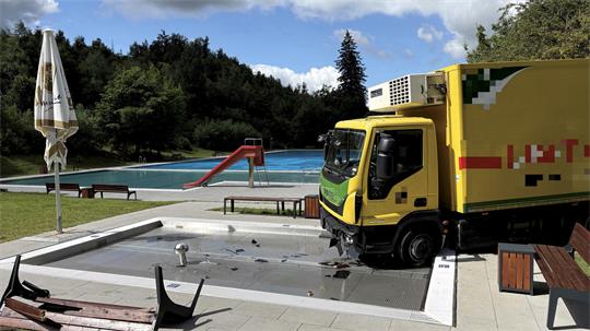 Gelber Lkw steht in einem Schwimmbecken.
