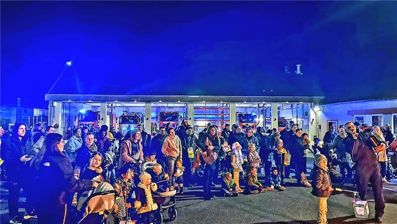 Familien stehen mit Laternen vor der Feuerwehrwache.