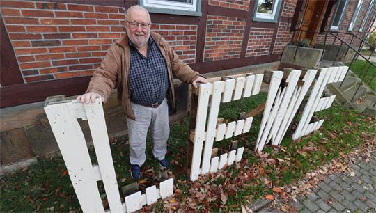 Ein Mann steht hinter dem aus Palettenholz gefertigten Schriftzug "Lewe".