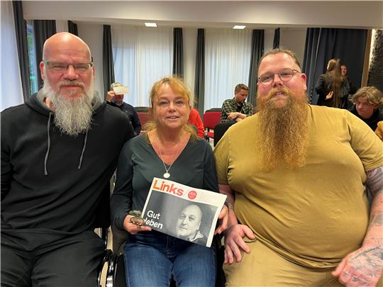 Zwei Männer und eine Frau blicken in die Kamera.