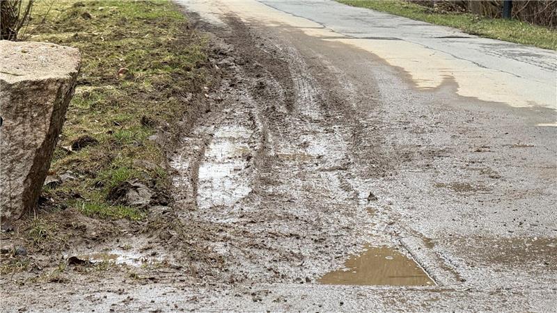 Das Foto zeigt einen matschigen Rasen neben einer asphaltierten Fahrbahn.