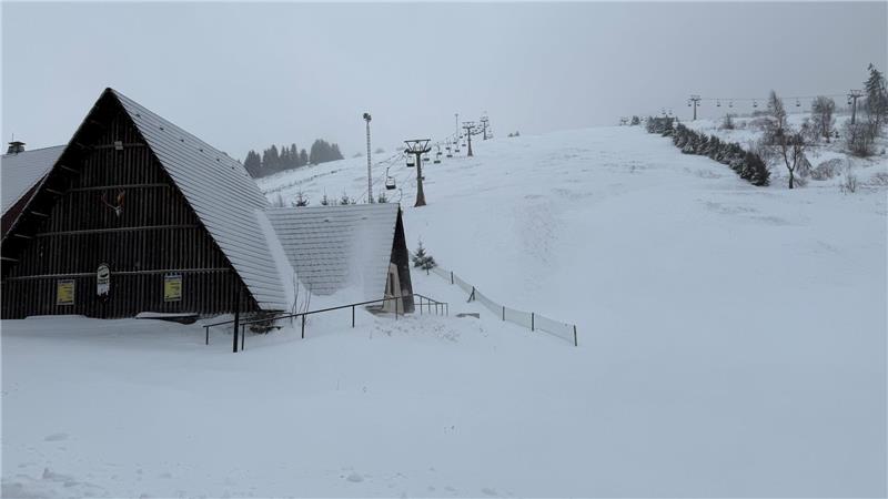 Das Foto zeigt ein verschneites Gebäude und einen Sessellift im Hintergrund.
