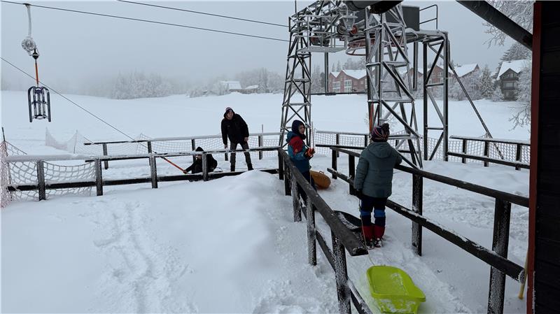 Kinder warten vor einem Rodellift darauf, dass sie den Hang hinaufgezogen werden.