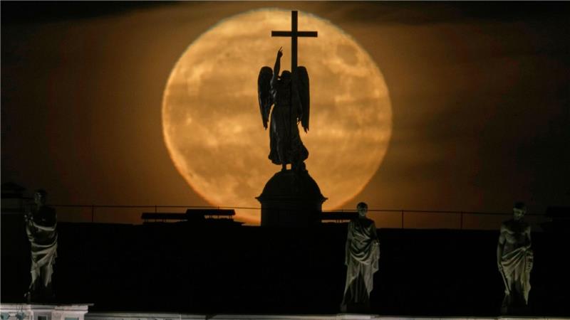 Der Mond geht hinter einer Engelsstatue auf der Alexandersäule auf dem Palastplatz über St. Petersburg auf.