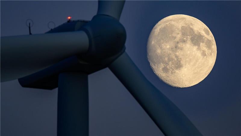 Der Mond ist hinter einer Windenergieanlage in Brandenburg zu sehen.