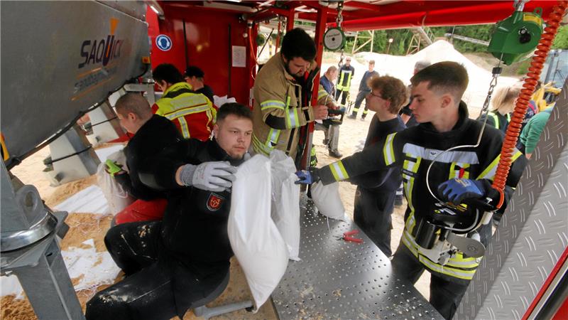 Der Nächste bitte: Links erfolgt das Füllen des Sandsacks, dann werden sie nach hinten gereicht, um sie zuzunähen.