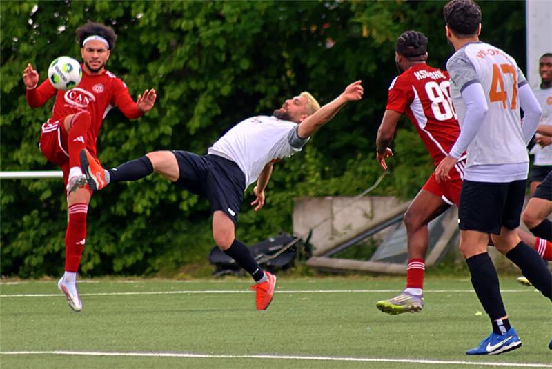 Fußballspieler in Aktion auf dem Spielfeld, einer führt einen Fallrückzieher aus, andere beobachten oder bewegen sich in Richtung Ball