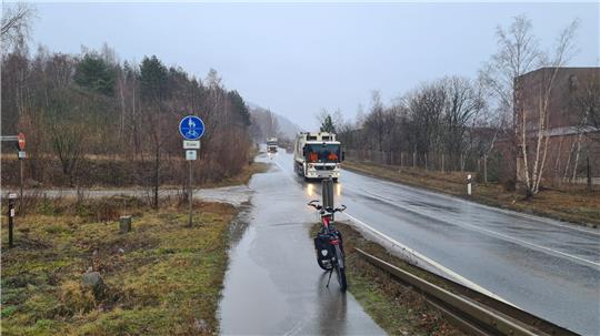 Ein Rad steht im Regen auf einem Radweg, der plötzlich endet.