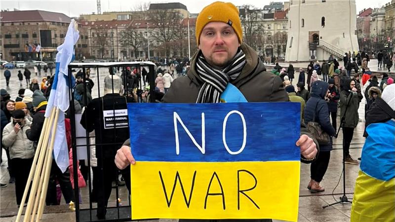 Der Russe Alexander Medvedev hält auf einer Demonstration in Litauen ein blau-gelbes Schild hoch, auf dem "No war" (Kein Krieg) steht.