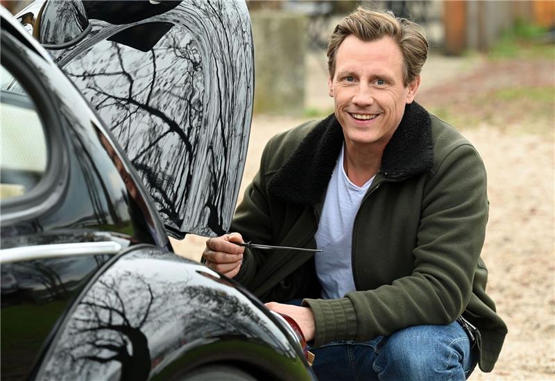 Der Schauspieler Patrick Kalupa mit seinem Oldtimer VW Käfer.