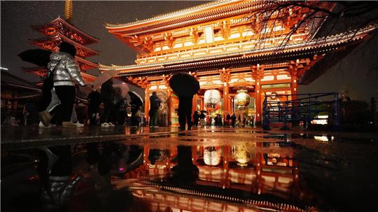 Der Sensoji-Tempel spiegelt sich in einer Pfütze, als Menschen zum Neujahrsgebet in Tokio ankommen.