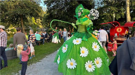 Das Foto zeigt eine Person auf Stelzen auf einer Festmeile.