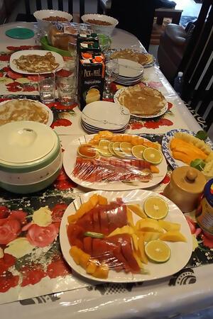 Das Bild zeigt einen Tisch mit vielen Tellern, auf denen sich neben Obst, auch ein dünnes Fladenbrot, genannt Chapati befindet.