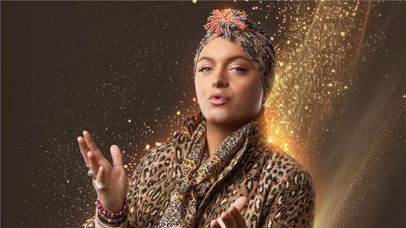 Ein Mann in Frauenkleidern und mit Turban blickt in die Kamera.