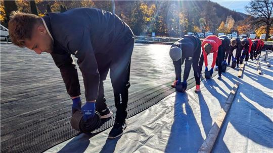 Die Herrenmannschaft des VfB Germania Halberstadt rollt an einem Tag die Gummimatten der Eisbahn aus.