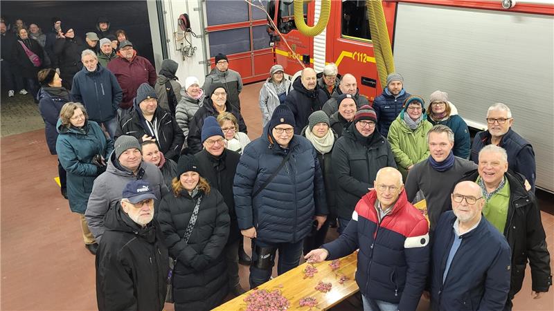 Der GZ-Schweinchenverkauf läuft in Goslar auf Hochtouren Gruppe von Menschen in Winterjacken steht in einer Halle vor einem roten Feuerwehrfahrzeug und einem Holztisch mit verstreuten Gegenständen