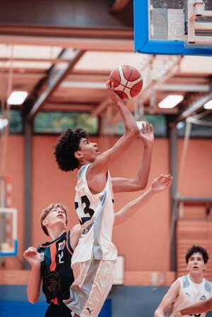 Ein Goslarer auf den Spuren von Dennis Schröder Junger Basketballspieler in weißem Trikot springt zum Korb, um den Ball zu werfen, zwei weitere Spieler beobachten.