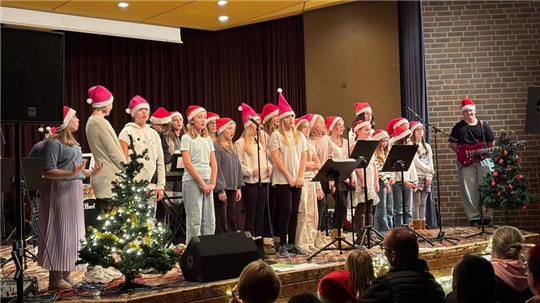 Der Weihnachtschor der 5. und 6. Klassen sorgt mit Weihnachtsmützen und bekannten Weihnachtsliedern für eine festliche Stimmung.
