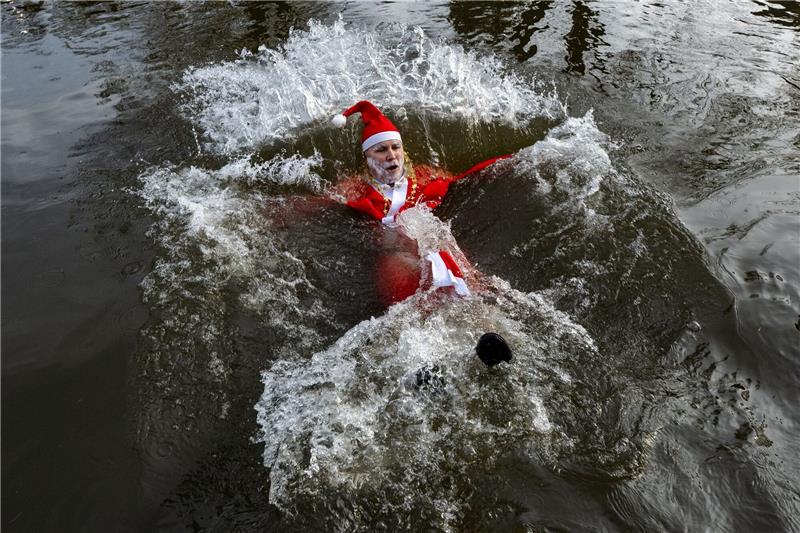 Der Weihnachtsmann lässt sich beim Silvesterbaden Tschechien im Fluss Mettau treiben.