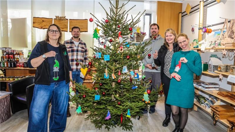 Fünf Personen stehen um einen geschmückten Weihnachtsbaum herum.