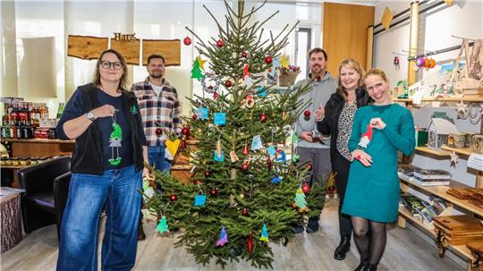 Fünf Personen stehen um einen geschmückten Weihnachtsbaum herum.