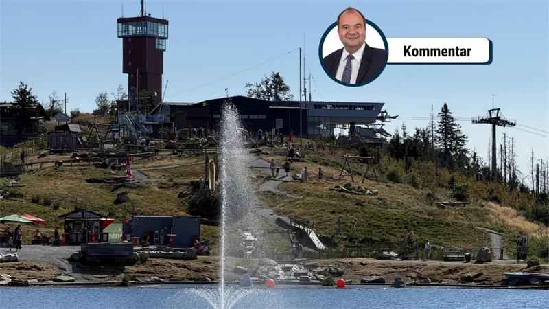 Das Foto zeigt einen Aussichtsturm auf einem Berg vor einem See mit einem Springbrunnen.