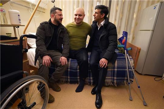 Der britische Premier Rishi Sunak (r) und der ukrainische Präsident Wolodymyr Selenskyj (l) treffen einen verwundeten Kriegsveteranen.