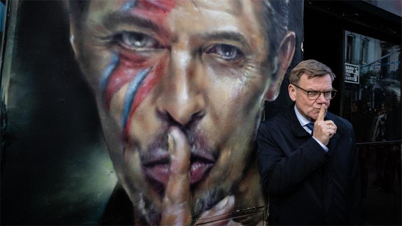 Der deutsche Außenminister Johann Wadephul (CDU) steht bei einem Rundgang durch das Stadtzentrum von Buenos Aires neben einem Graffiti von David Bowie.
